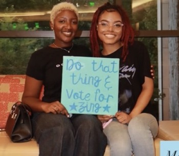 Nzinga and a fellow student smiling together with a Vote for Zing sign