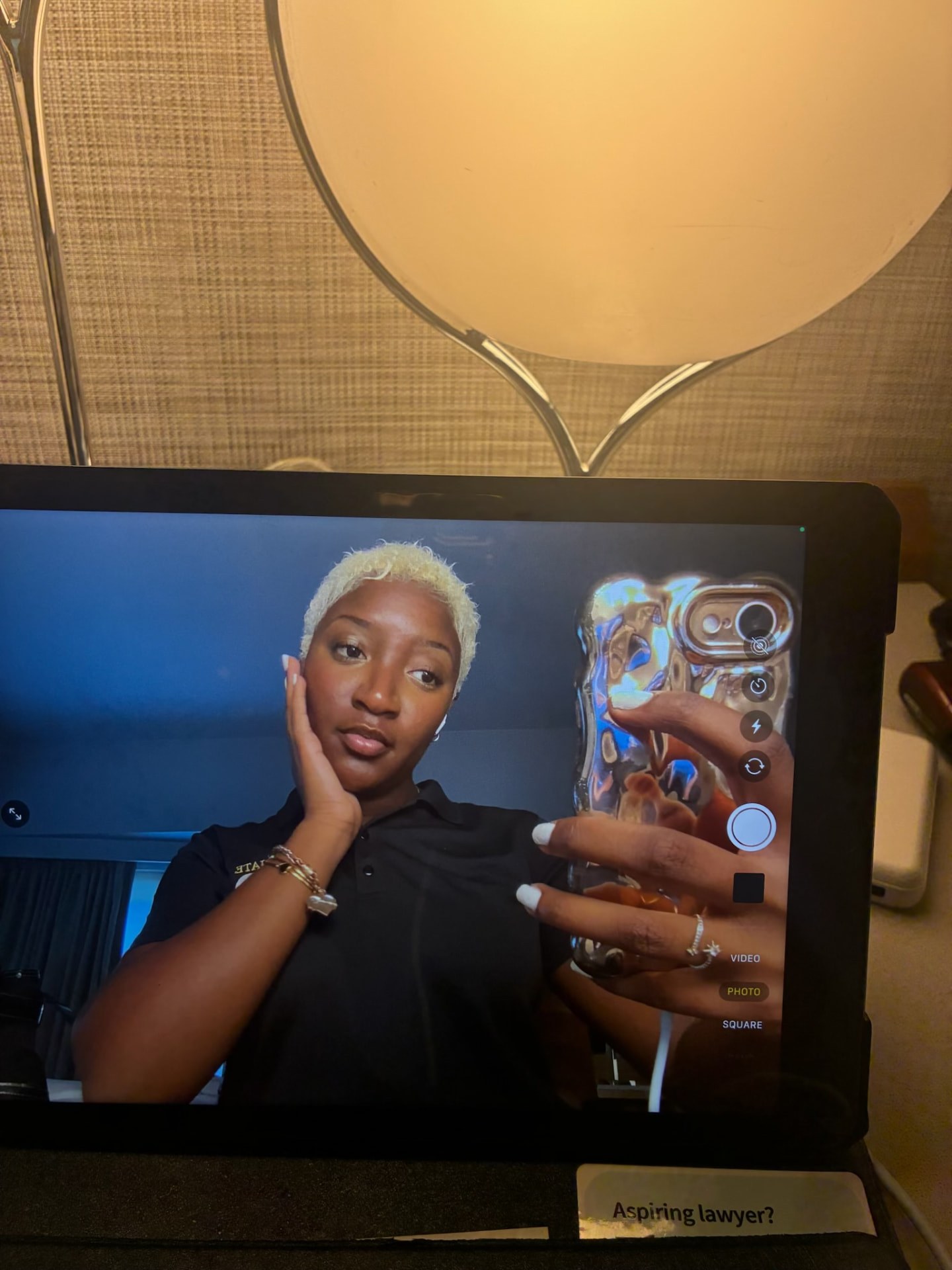 Nzinga posing for a camera preview on a tablet screen beside a warm lamp