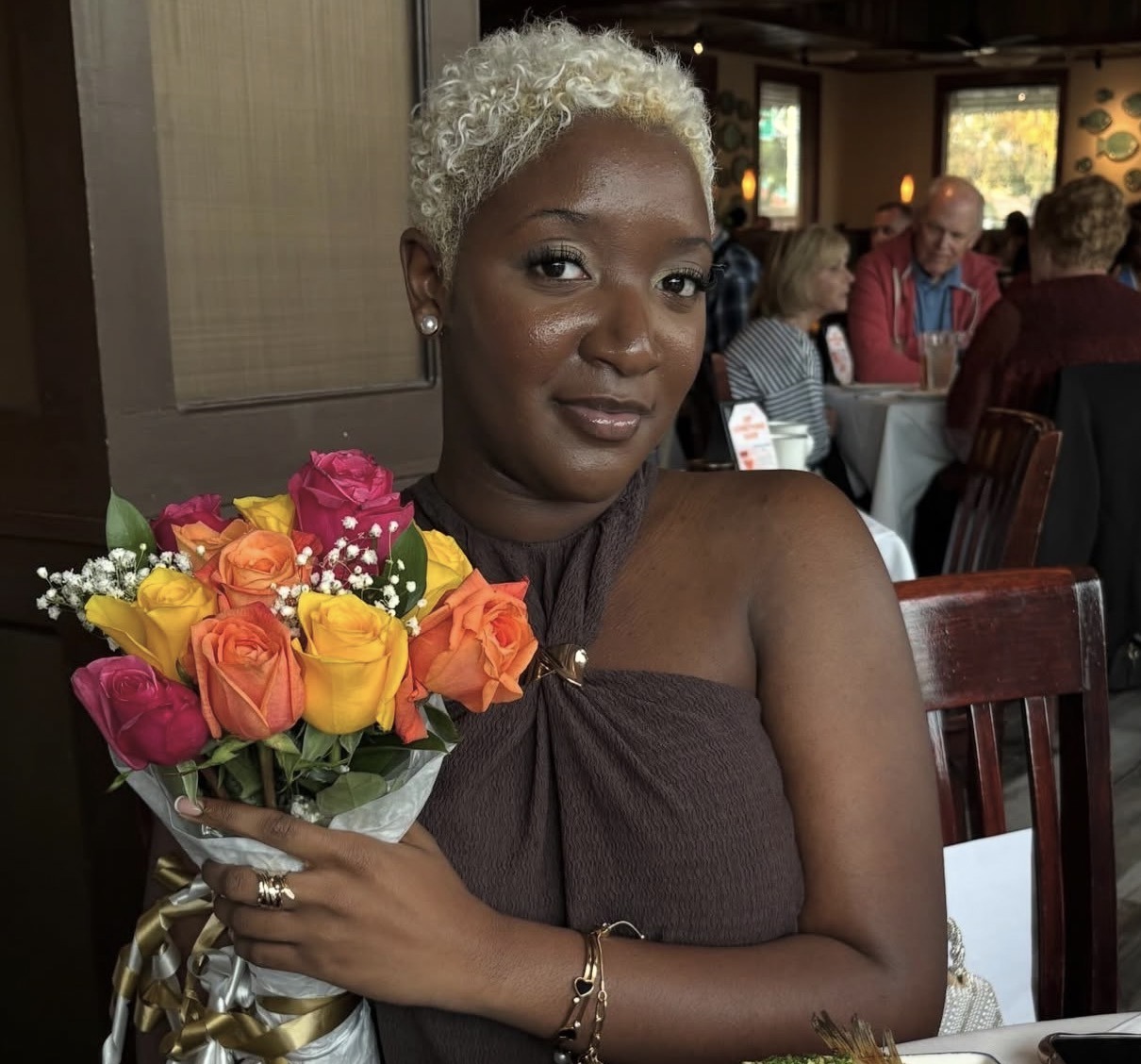 Nzinga holding a colorful bouquet at a restaurant